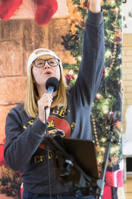 young girl singing with hand raised and christmas tree